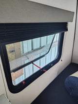 perfect for travel. Features dark blue quilted bedding and a cheerful lemon-slice pillow.|RV rental interior: modern bunk beds with a window and wood-look flooring