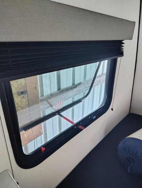  perfect for travel. Features dark blue quilted bedding and a cheerful lemon-slice pillow.|RV rental interior: modern bunk beds with a window and wood-look flooring