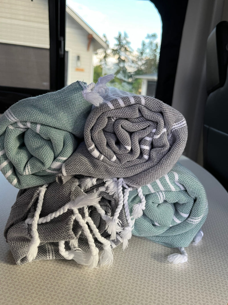 Three neatly rolled green and gray towels with white stripes and tassels, resting in an RV rental. — photo 6