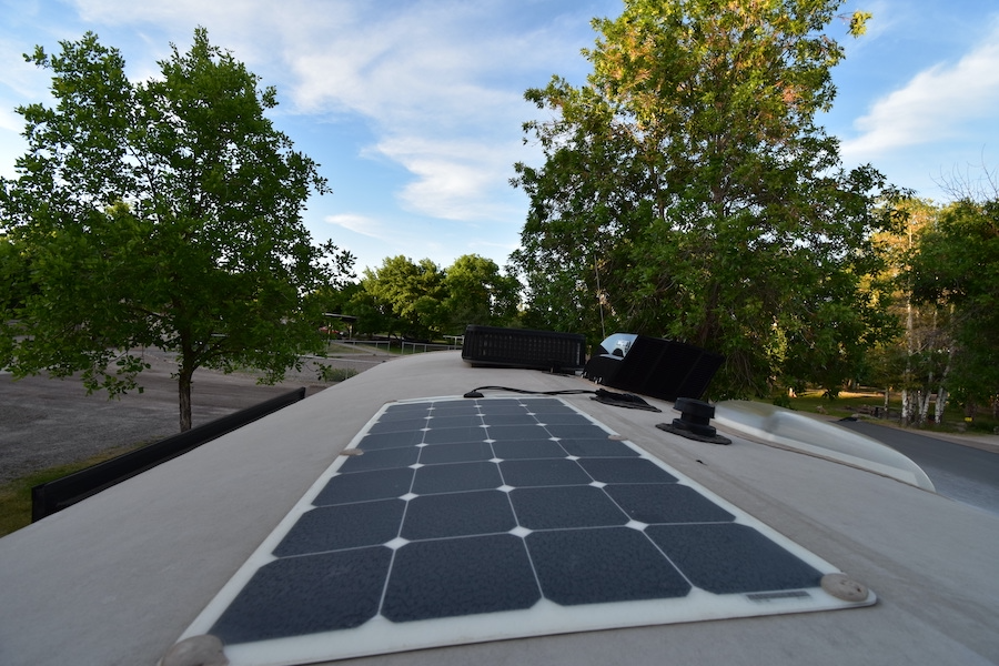 RV rental's rooftop solar panel and vents under a blue sky, ideal for off-grid camping adventures.