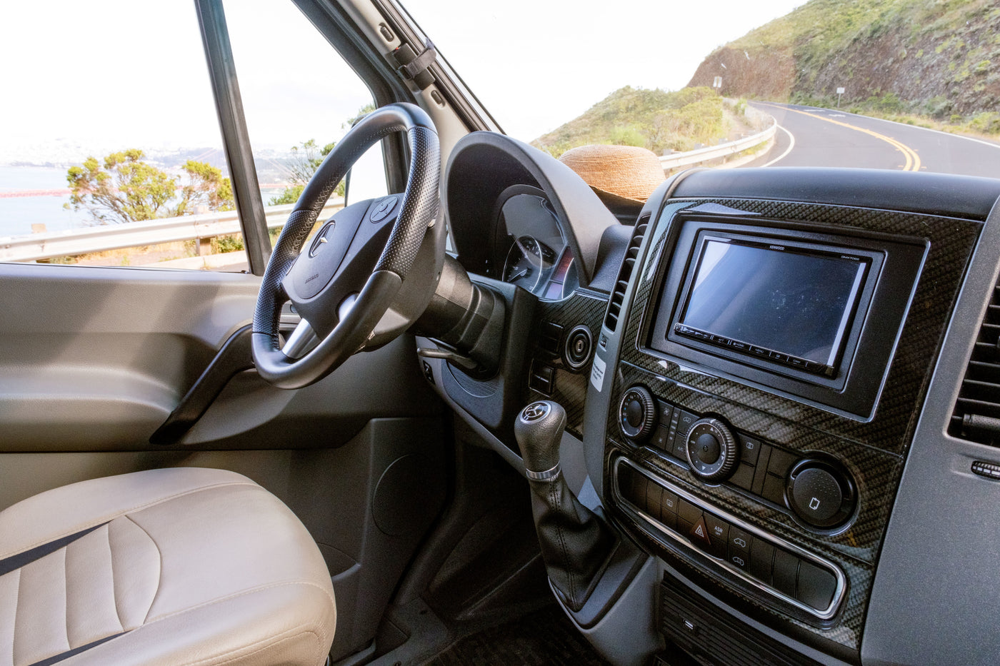 Driver's view from an RV rental: cockpit with detailed dashboard, steering wheel, and scenic coastal road ahead for adventure. — photo 15