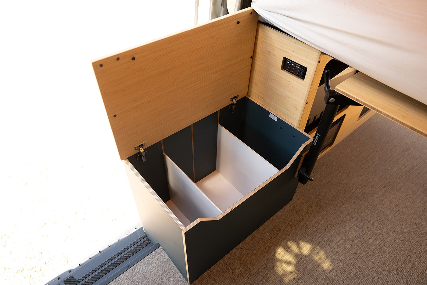 See efficient storage in this RV rental: an open-lid box with interior dividers and a pull-out table arm. — photo 10