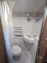 Compact RV rental bathroom with toilet, sink, and shower – practical for travel.