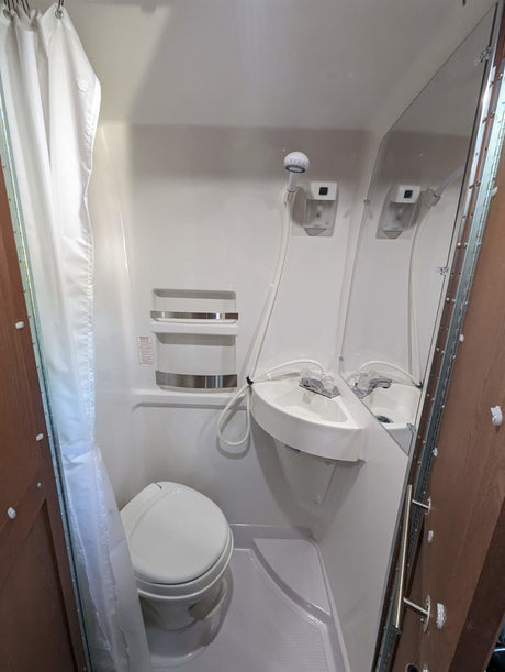 Compact RV rental bathroom with toilet, sink, and shower – practical for travel.