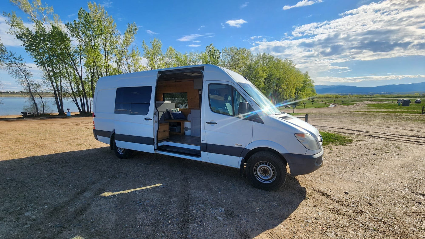  and stunning red rock views.|A white RV rental is parked in a vast red desert landscape with distant mesas under a bright blue sky.|White camper van (RV rental) parked by a lake. Open door shows cozy interior — photo 1