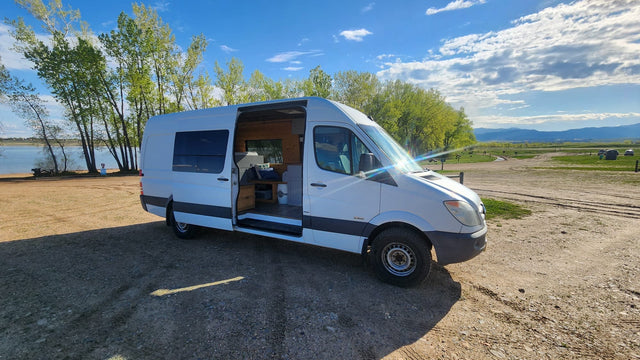  and stunning red rock views.|A white RV rental is parked in a vast red desert landscape with distant mesas under a bright blue sky.|White camper van (RV rental) parked by a lake. Open door shows cozy interior