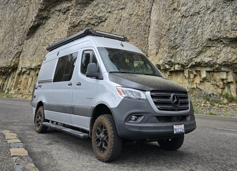 Adventure awaits with this custom Mercedes Sprinter van, ideal for rv rental trips. Parked roadside by a textured rock face. — photo 1