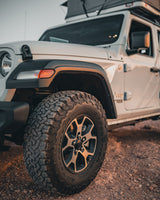 White Jeep with rugged tires and rooftop tent parked on a dirt path. Ideal for an outdoor adventure or a unique RV rental experience.