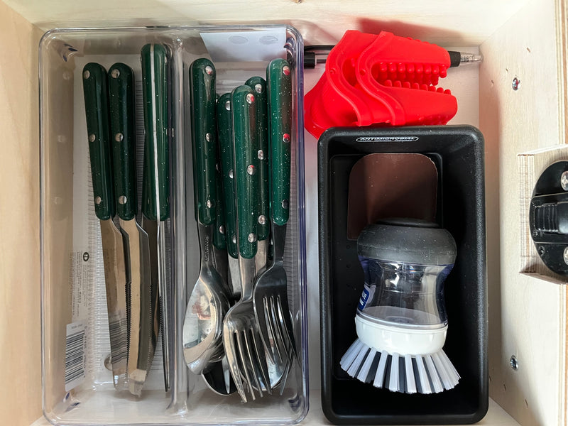 RV rental kitchen: Organized green cutlery, a fun red T-Rex grabber, and an antimicrobial dish brush caddy for compact living. — photo 9