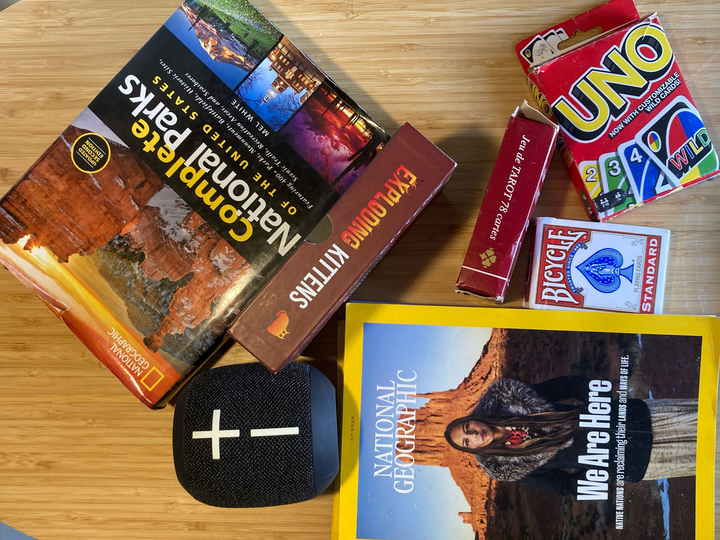 Packing for an RV rental trip: National Parks guide, games (UNO, Exploding Kittens), & a speaker for onboard fun.