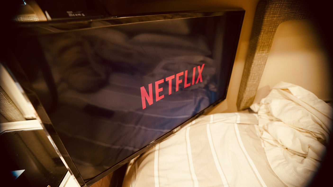Netflix on TV in a cozy RV rental, with striped bedding visible. Enjoy home comfort while traveling.