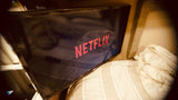 Netflix on TV in a cozy RV rental, with striped bedding visible. Enjoy home comfort while traveling.