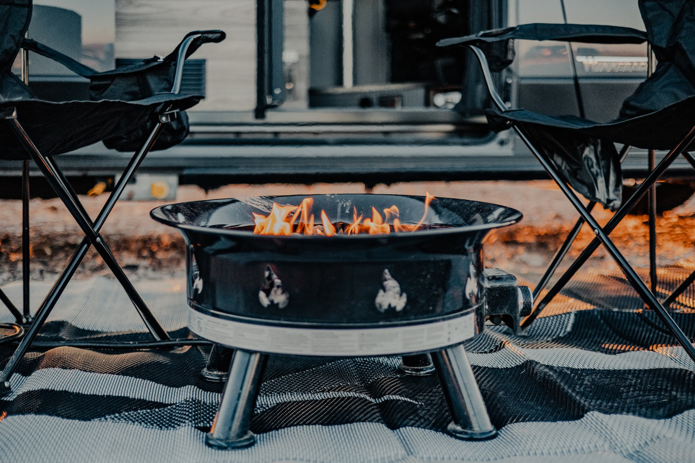 An RV rental setup: a glowing fire pit, comfy camping chairs, and a striped mat create a perfect outdoor evening. — photo 12