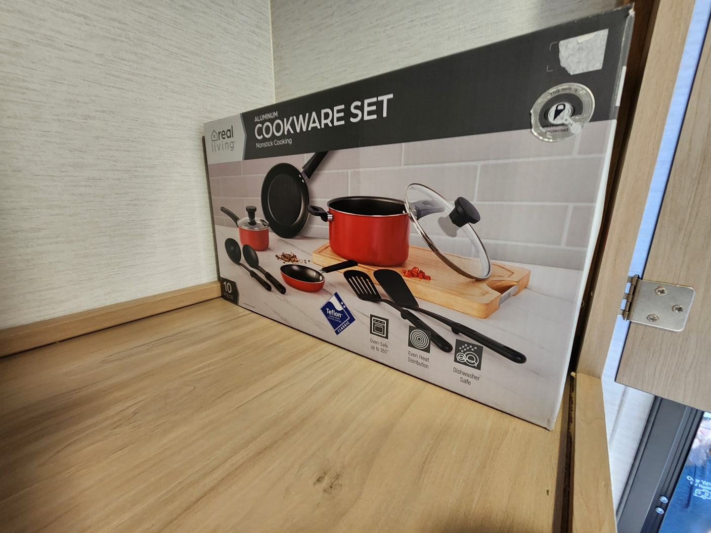 A Real Living Cookware Set box sits in an RV rental kitchen cupboard, ready for your next adventure.