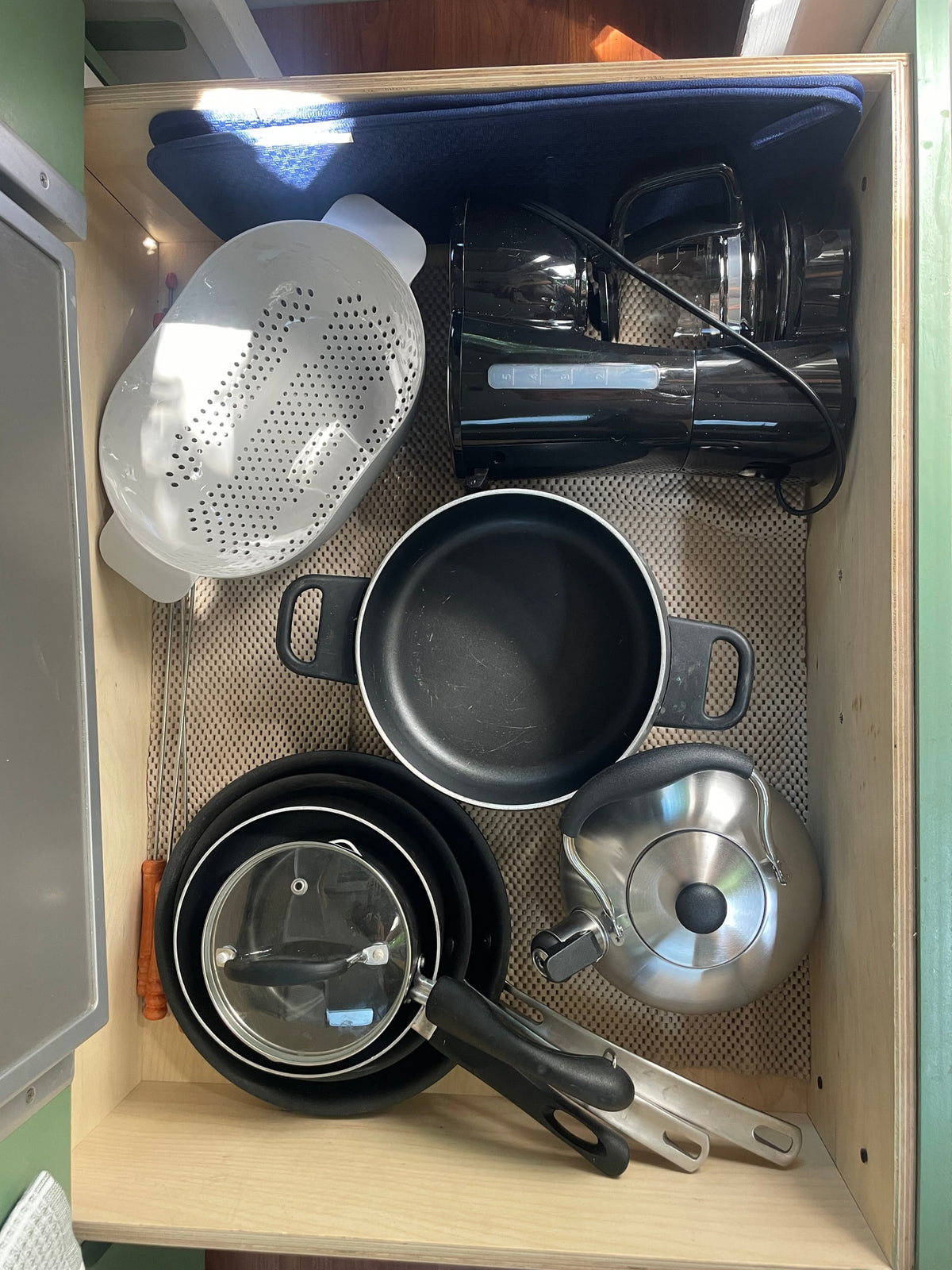 Efficient RV rental kitchen drawer: organized pots, pans, kettle, colander, and coffee maker on non-slip mat. — photo 2
