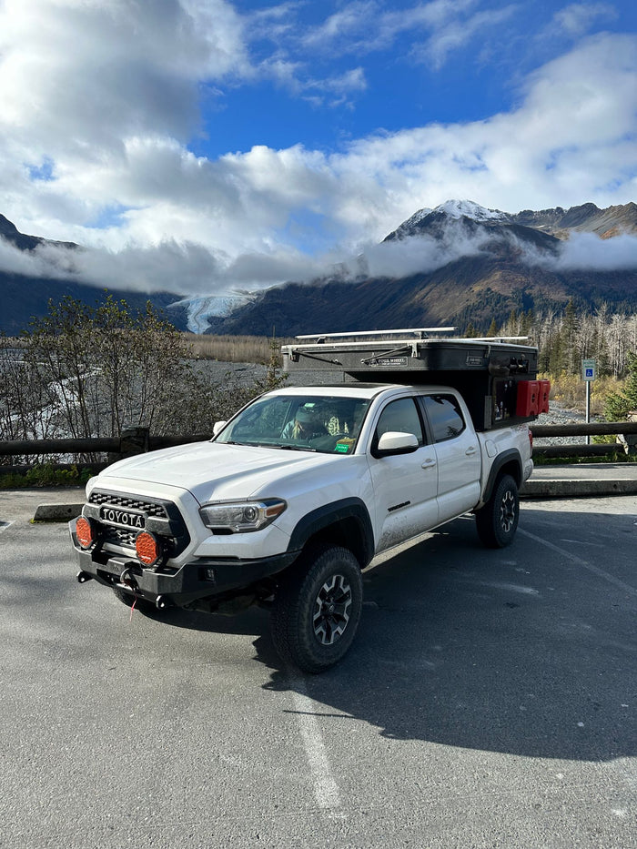 and picnic table.|White truck camper on sandy beach at sunset