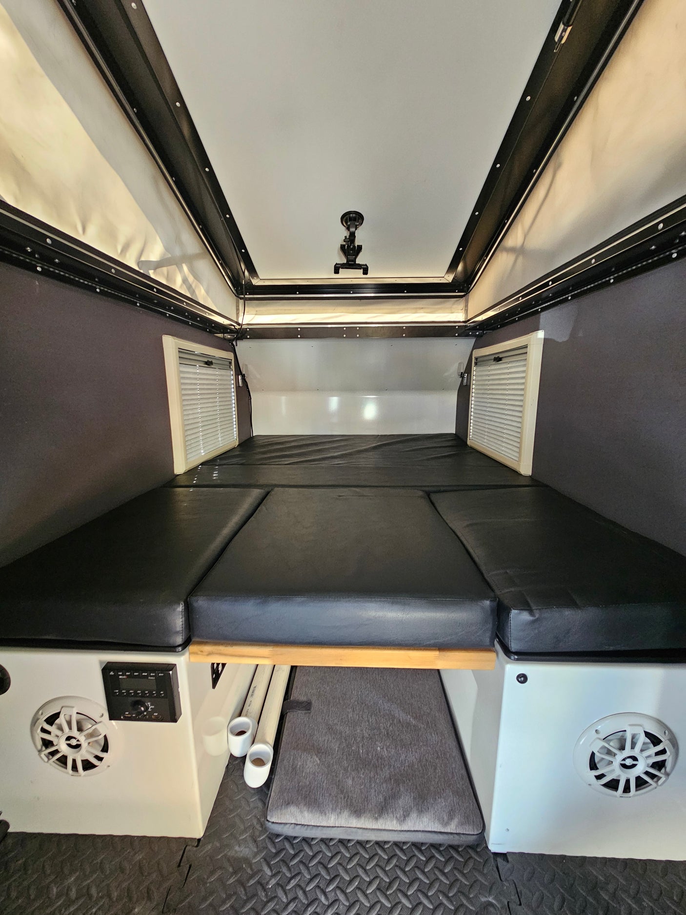 Inside a compact RV rental, featuring a comfortable convertible bed, pop-top roof, and integrated controls.