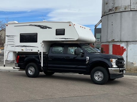 A black Ford pickup truck fitted with a white Northstar truck camper, an excellent option for an RV rental.
