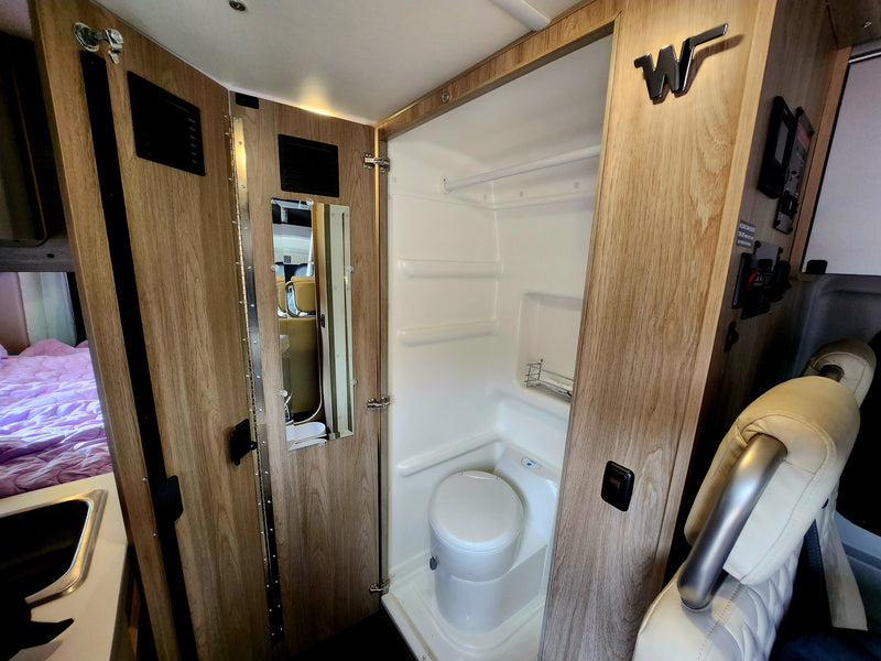  and a comfortable bed in the back of the camper van.|Compact RV rental kitchen featuring a Suburban stove — photo 3