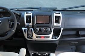 RV rental interior: driver's dashboard with steering wheel, central screen, climate controls, and gear shifter. — photo 12