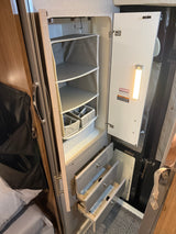 Organized RV rental closet featuring hanging storage, pull-out drawers, and an LED light for efficient space use.