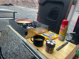 Enjoying outdoor breakfast in an RV rental. Eggs frying on a portable stove with coffee, spices, and cooking spray ready.