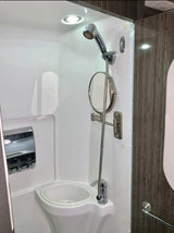 Inside an rv rental: compact shower stall with a handheld shower, sink, mirror, and soap dispenser. Space-saving design.
