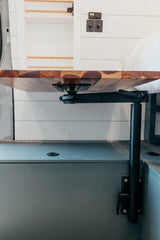 Custom RV rental interior featuring an adjustable wooden table, white shiplap walls, and system controls.