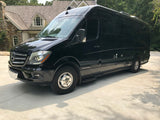 A sleek black Airstream Mercedes-Benz Sprinter RV rental, perfect for luxury road trips, is parked on a sunlit driveway.
