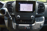 Modern RV rental interior: infotainment screen showing phone connection, gear shift, climate controls, USB ports, and 12V DC outlet.