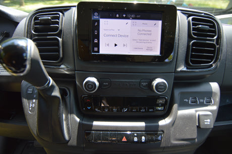 Modern RV rental interior: infotainment screen showing phone connection, gear shift, climate controls, USB ports, and 12V DC outlet.