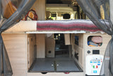 An RV rental's clever interior: a raised bed, under-bed storage, pull-out floor, and a utility panel for water/power.