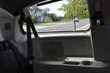 Inside a bright RV rental: passenger seat, side panel with speaker, and a clear view of a suburban road.