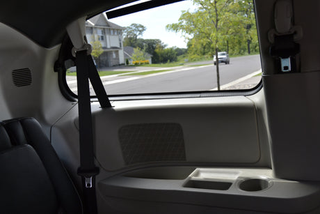 Inside a bright RV rental: passenger seat, side panel with speaker, and a clear view of a suburban road.