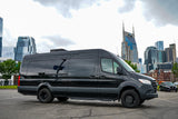 A black Mercedes-Benz Sprinter RV rental in an urban lot, with the Nashville skyline including the AT&T building.