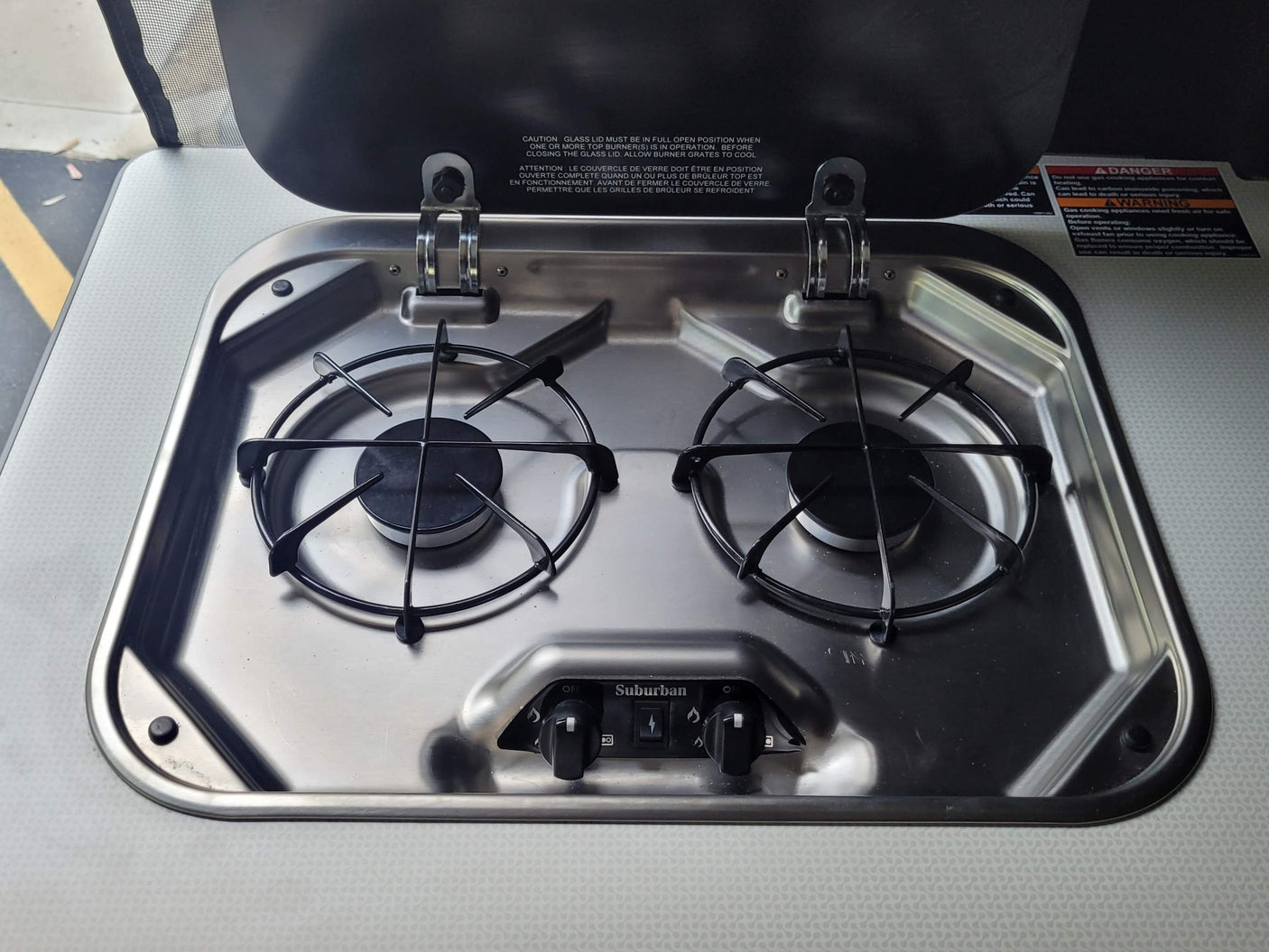 Stainless steel two-burner gas stove in an RV rental kitchenette, ready for camping meals.