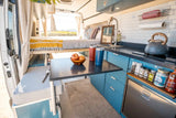 Modern RV rental: a compact camper van interior with an elevated bed, kitchenette, and table. Ready for adventure.