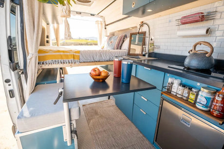 Modern RV rental: a compact camper van interior with an elevated bed, kitchenette, and table. Ready for adventure.