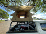 This truck with a tan rooftop tent offers portable lodging, perfect for your next outdoor rv rental adventure.
