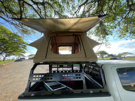 This truck with a tan rooftop tent offers portable lodging, perfect for your next outdoor rv rental adventure.