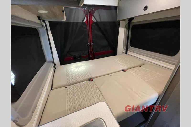  parked at a dealership lot under a blue sky.|RV rental interior: view from the rear showing front cockpit — photo 7