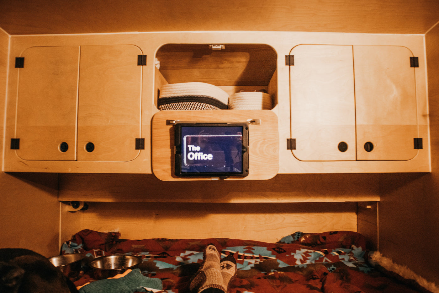 Relax in a cozy RV rental: watching "The Office" on a tablet in a wooden interior with storage and pet bowls. — photo 10