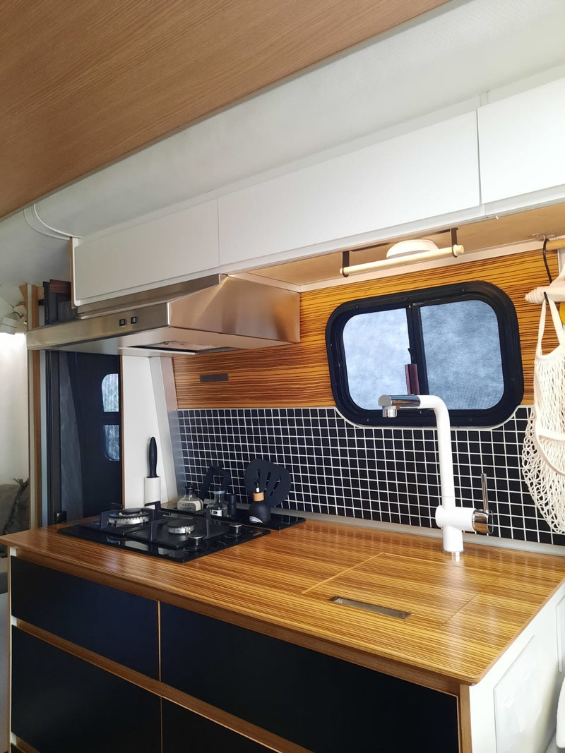 Modern RV rental kitchen with wood-patterned counters, black & white tiles, and essential appliances for comfortable travel. — photo 2