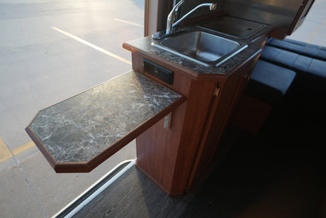 Inside your RV rental: a compact kitchen with a sink, extendable counter, and USB ports. Designed for convenient travel amenities.
