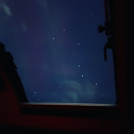 Stargazing in your rv rental: deep blue night sky with bright scattered points and faint clouds, framed by a window.