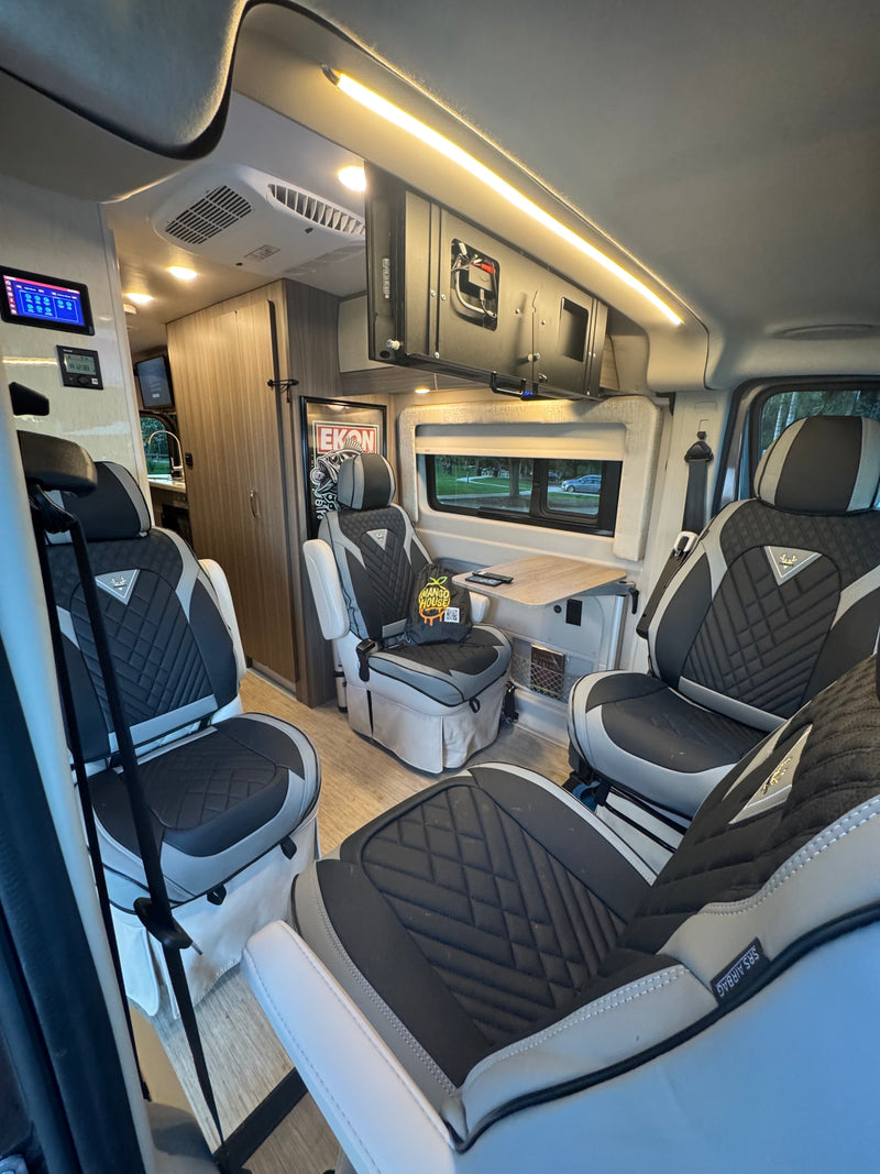 Experience a comfortable rv rental interior: plush seating, a dining table, modern controls, and ambient lighting for luxury mobile living. — photo 13