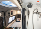 RV rental interior: View from the shower area into the comfy sleeping and living space of a modern campervan.
