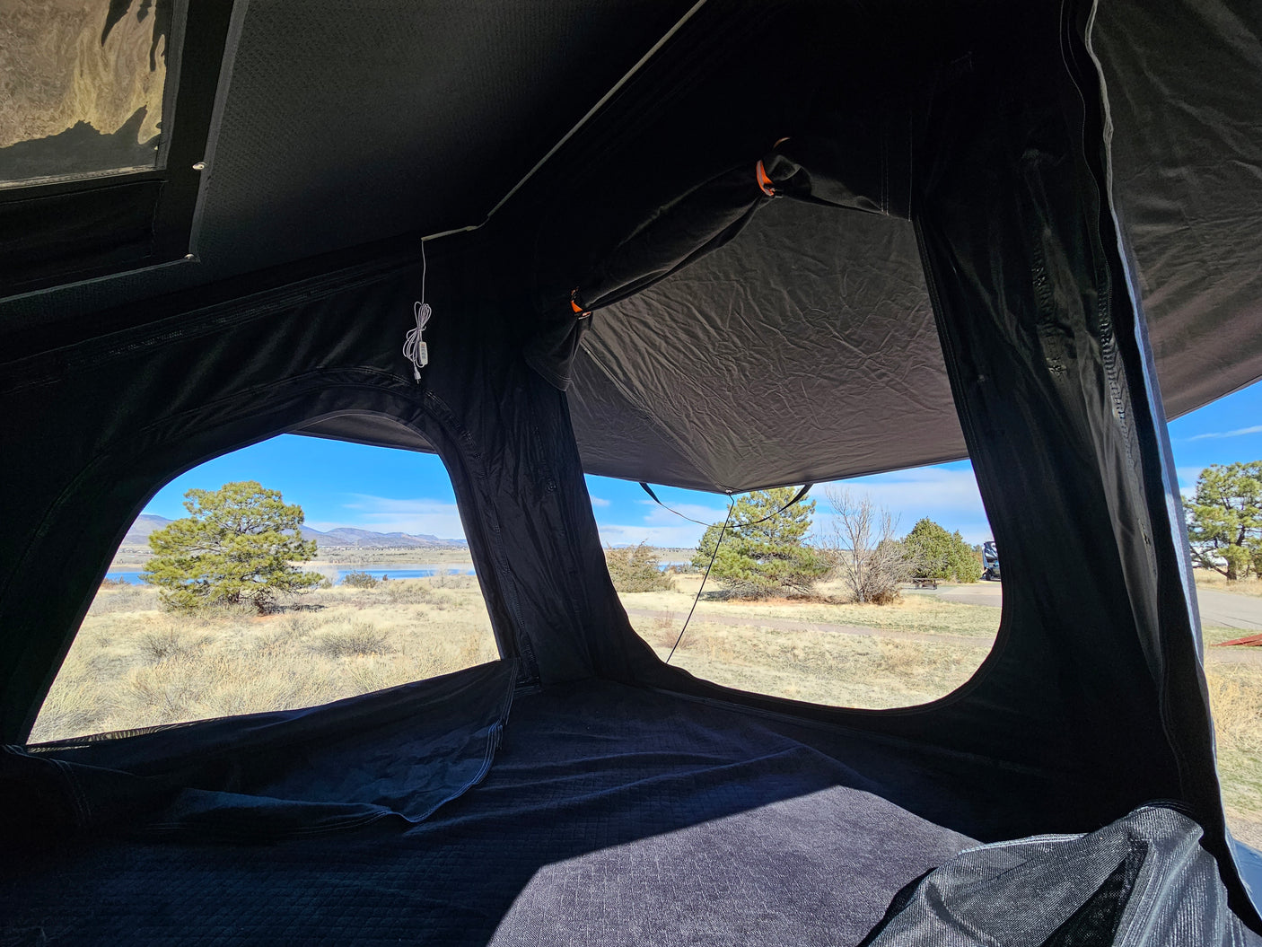 Inside a spacious rooftop tent with stunning lake and mountain views from an RV rental trip. Perfect camping!
