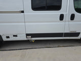 Side view of a white Winnebago RV rental, showing sliding door, windows, and external utility connections.