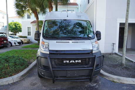Front view of a silver Ram ProMaster Winnebago RV rental van with a brush guard, parked in a sunny residential area.